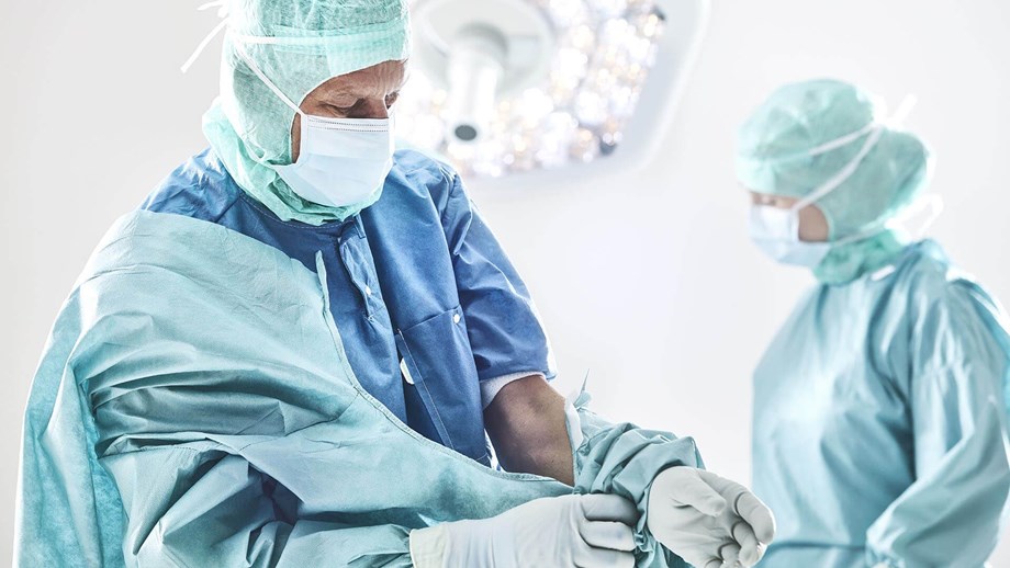 Kirurg paneb enne operatsiooni kitli selga